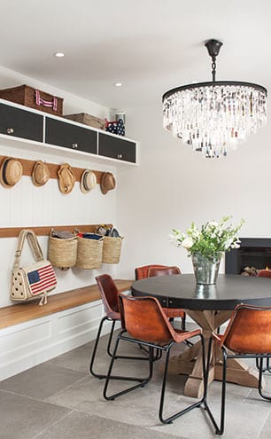 The circular table is surrounded by leather dining chairs from Rockett St George in the boot room area of the kitchen, with personalised storage and hooks