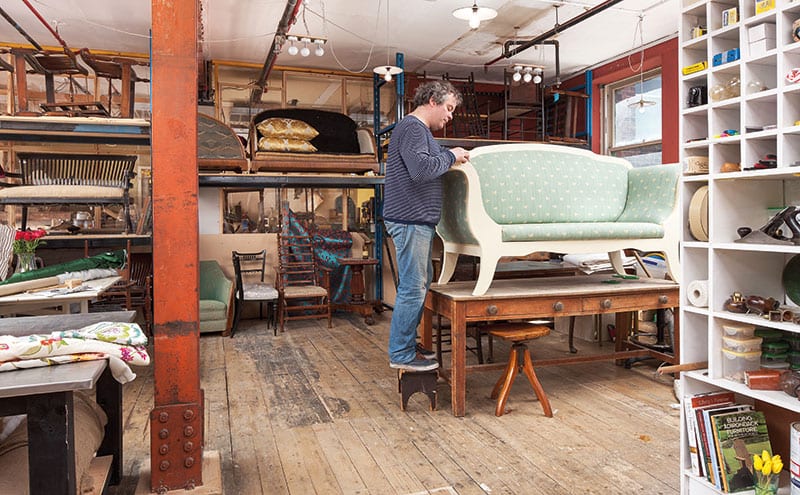 John puts the finishing touches to a Swedish couch upholstered in Bayberry Strie fabric by Brunschwig & Fils.