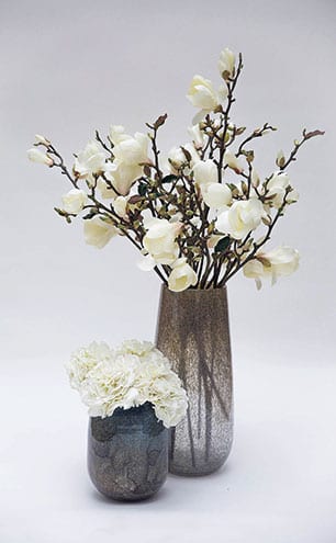 Bloomed and Budding white magnolia stems in bubble glass vase, from £395; white hydrangeas in duo tone thick glass vase, from £195, Lifelike Flowers.