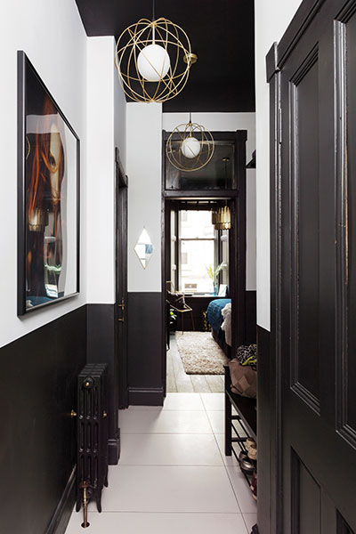 the brass and black combination extends the hall, where the upper portion of each wall has been painted white to bring brightness into the central part of the house