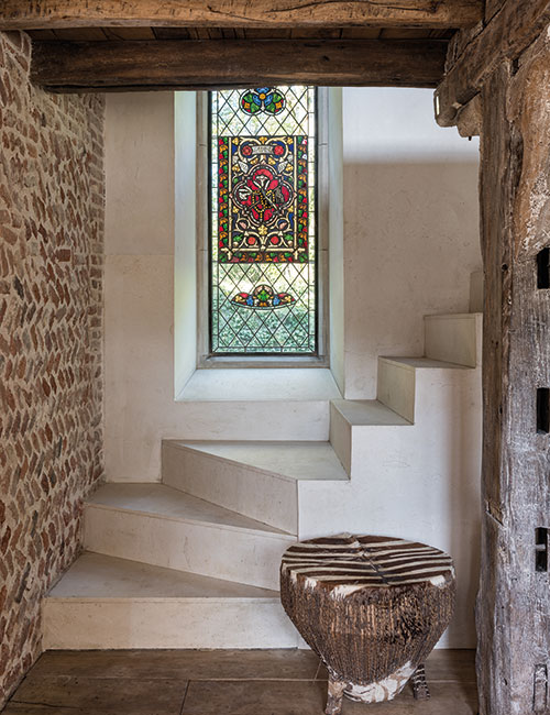 The simple helical staircase, built of Spanish limestone, was designed by McNeill. Fragments of medieval stained glass were set into the tall leaded window, made by Bronze Casements