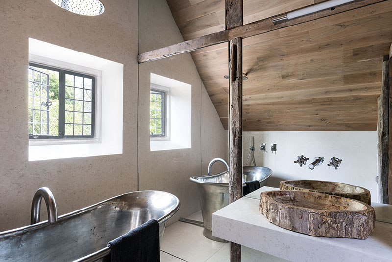 McNeill’s architectural approach to design can be seen in the small bathroom, where a mirrored wall bisected by reclaimed beams cleverly magnifies the sense of space. The fossilised wood basin was sourced in Indonesia, while Italian white marble was used for the floor and wall. The bath is from William Holland. All the windows in the house were made by Bronze Casements