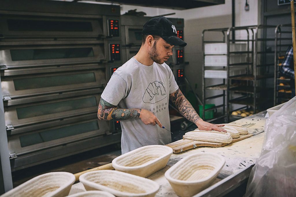 Lee-MacAloney,-one-of-the-Freedom-bakers,-scoring-sourdoughs-to-go-into-the-oven