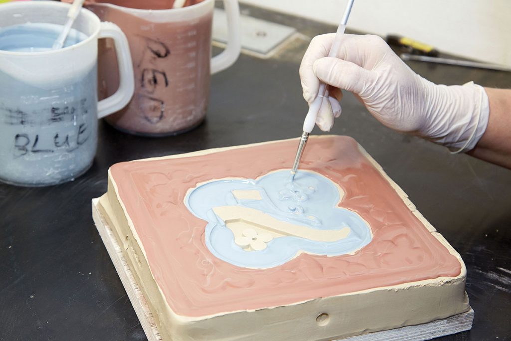 a-fine-brush-is-used-to-fill-different-coloured-liquid-slips-into-an-encaustic-tile