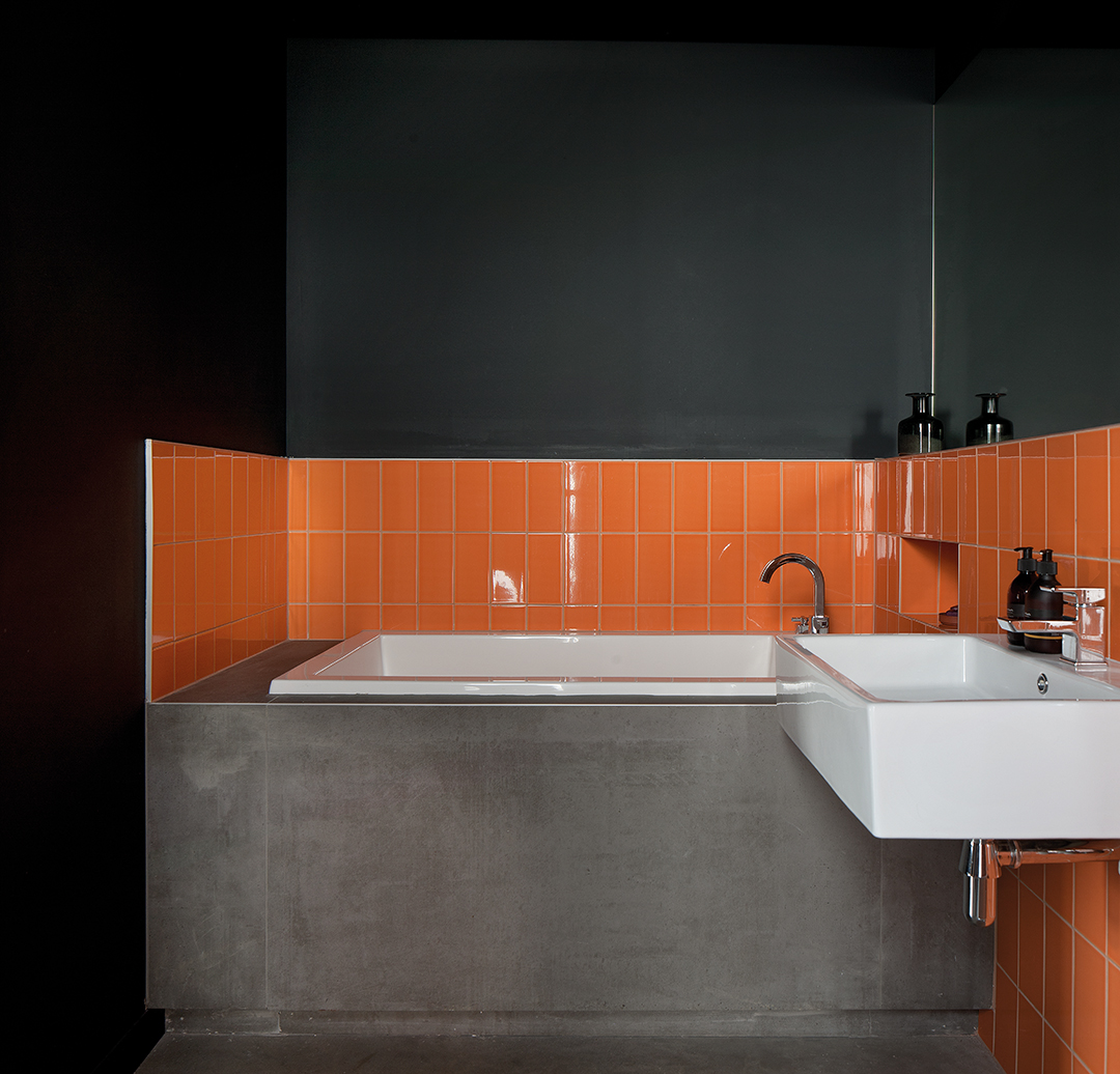 bathroom, bright orange tiles, stone bath, dark walls